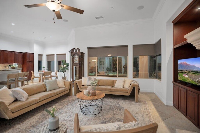 tiled living room featuring ceiling fan, crown molding, and a high ceiling