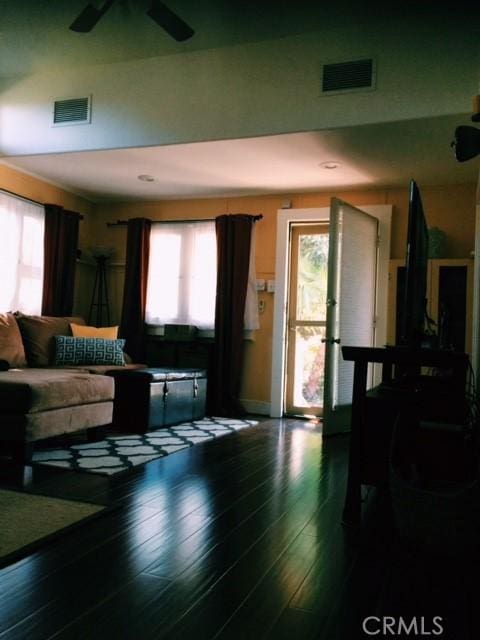 living room featuring ceiling fan, dark wood-type flooring, and plenty of natural light