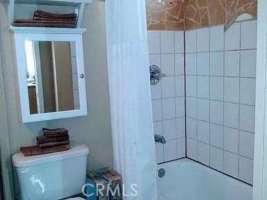 bathroom featuring toilet and tiled shower / bath