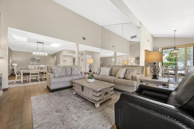 living room with a chandelier, high vaulted ceiling, and light hardwood / wood-style flooring