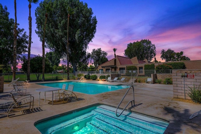 pool at dusk featuring a patio