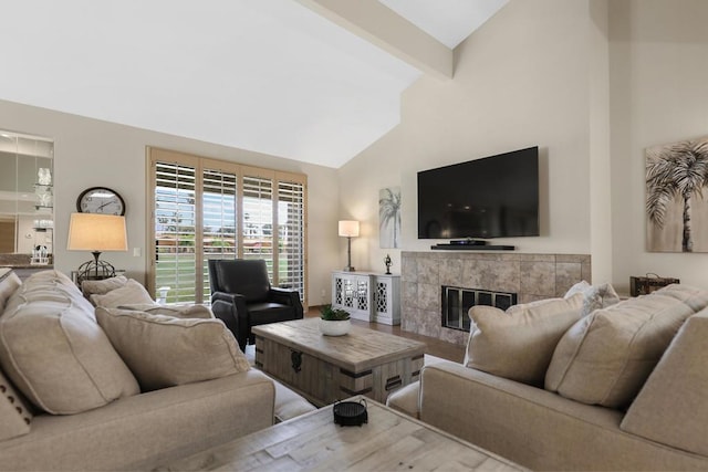 living room featuring a tiled fireplace, beamed ceiling, and high vaulted ceiling