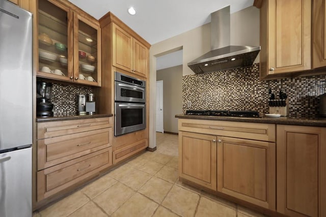 kitchen featuring wall chimney range hood, stainless steel appliances, light tile patterned floors, and tasteful backsplash