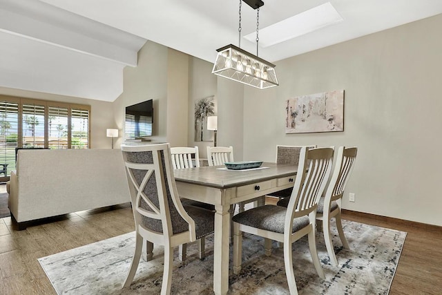 dining area with a chandelier, wood-type flooring, and lofted ceiling