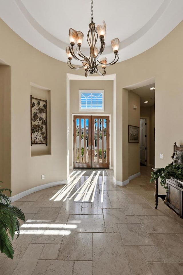 foyer entrance featuring a tray ceiling and a notable chandelier