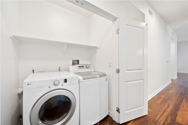 clothes washing area featuring dark hardwood / wood-style flooring and washer and clothes dryer