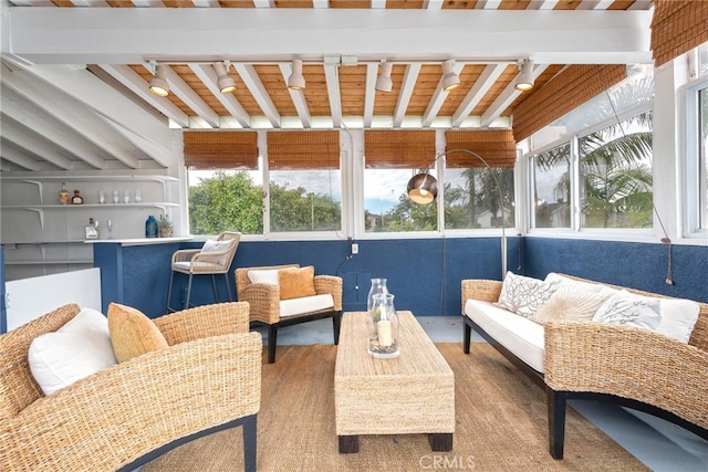 sunroom featuring track lighting and beamed ceiling