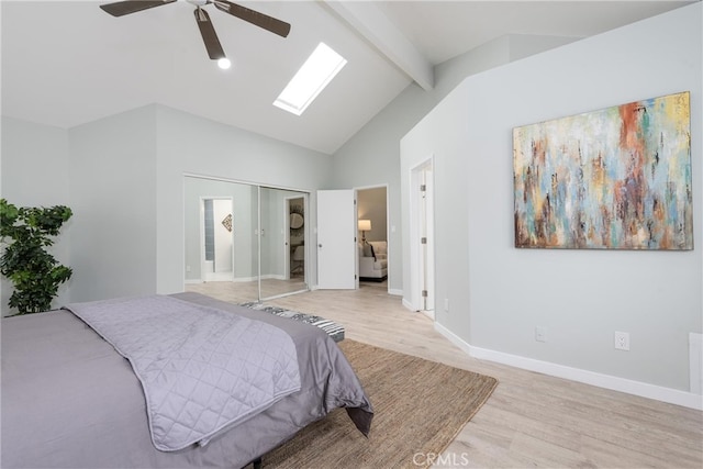 bedroom with a skylight, ceiling fan, a closet, beam ceiling, and light hardwood / wood-style flooring