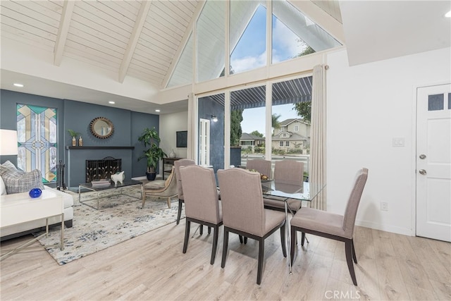 dining space with high vaulted ceiling, wooden ceiling, beam ceiling, and light wood-type flooring