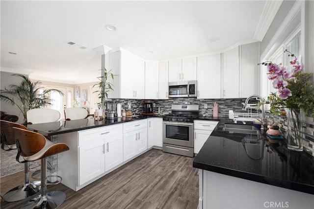 kitchen featuring white cabinetry, sink, stainless steel appliances, dark wood-type flooring, and kitchen peninsula