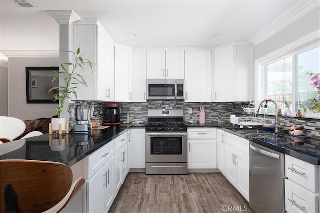 kitchen with sink, decorative backsplash, ornamental molding, white cabinetry, and stainless steel appliances