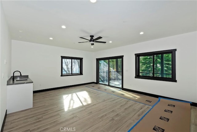 interior space with ceiling fan, sink, and light hardwood / wood-style flooring