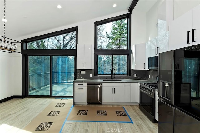 kitchen with black range with gas cooktop, pendant lighting, stainless steel dishwasher, white cabinets, and sink