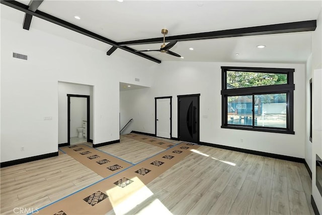 empty room featuring ceiling fan, light hardwood / wood-style floors, and beamed ceiling