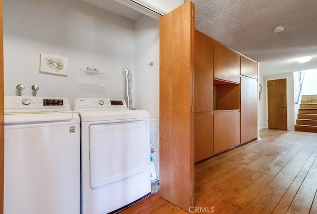 laundry area featuring light hardwood / wood-style floors, washing machine and dryer, and a textured ceiling