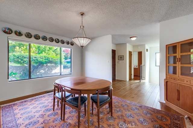 dining space featuring a textured ceiling and light wood-type flooring