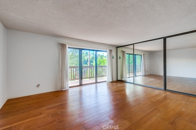 spare room with light wood-type flooring and a textured ceiling