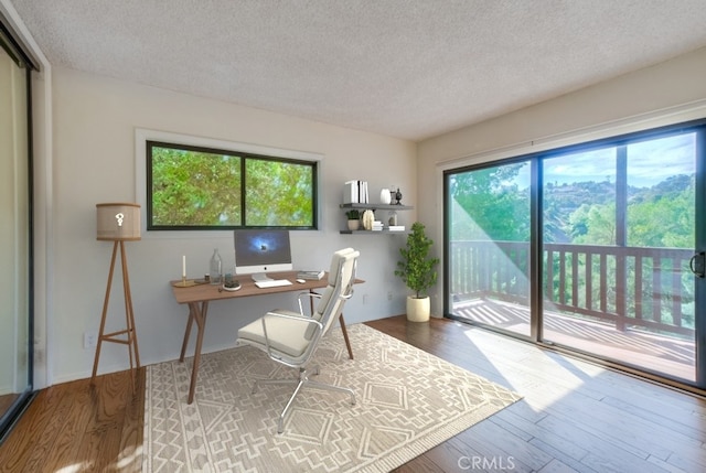 home office with hardwood / wood-style floors and a textured ceiling