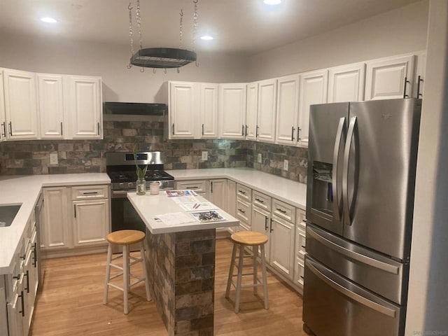 kitchen featuring stainless steel appliances, white cabinetry, a breakfast bar area, and light hardwood / wood-style flooring