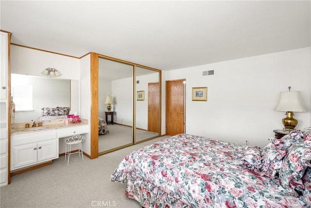 bedroom with light carpet, a closet, built in desk, and sink