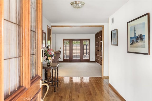 hallway with hardwood / wood-style floors and french doors