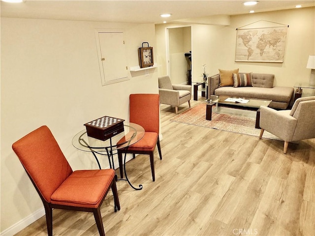 living area featuring recessed lighting, electric panel, baseboards, and light wood finished floors