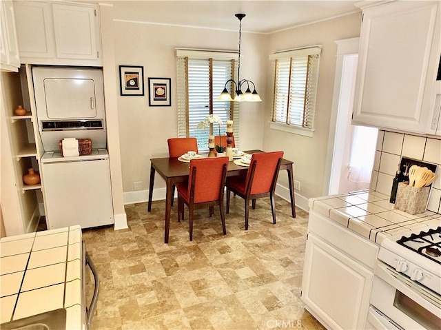 dining area with stacked washing maching and dryer, baseboards, and an inviting chandelier