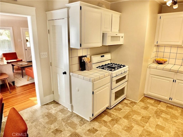 kitchen with tile countertops, white appliances, white cabinetry, and decorative backsplash