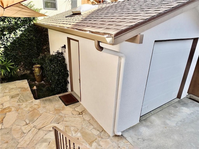 property entrance featuring a shingled roof and stucco siding