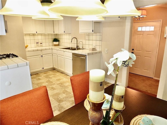 kitchen featuring tile counters, white cabinets, a sink, light floors, and stainless steel dishwasher