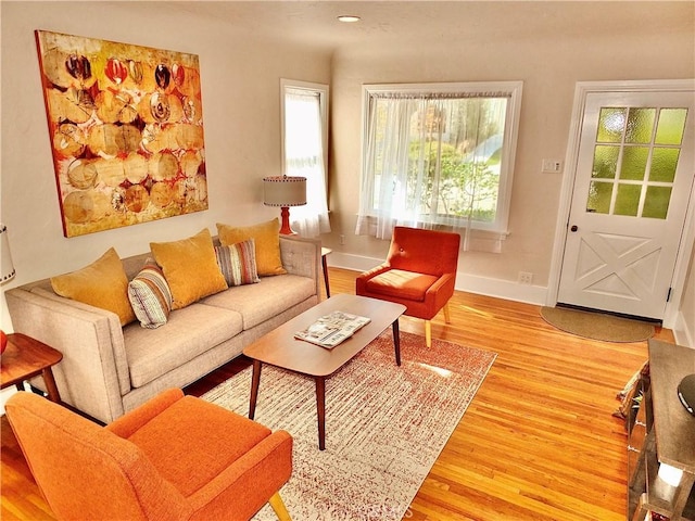 living room featuring light wood-style flooring, baseboards, and a wealth of natural light