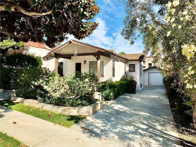 bungalow-style house with an outbuilding, driveway, and stucco siding