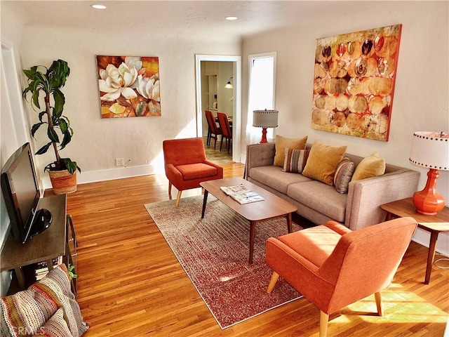 living room featuring baseboards, light wood-style flooring, and recessed lighting