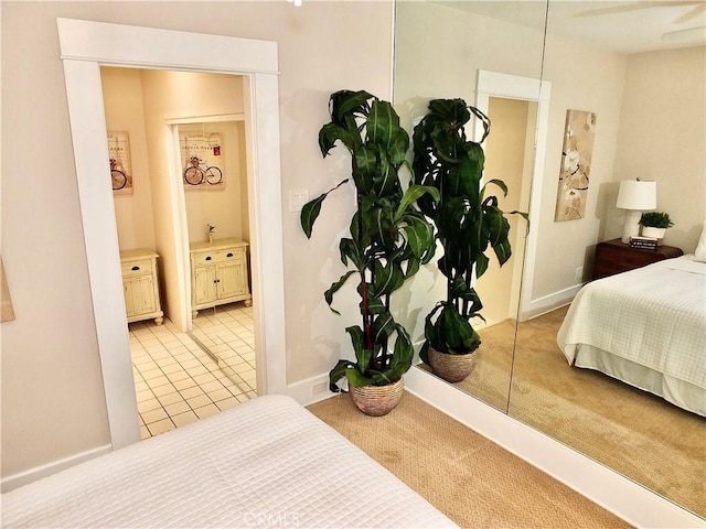 bedroom with light colored carpet, baseboards, light tile patterned flooring, and ensuite bath