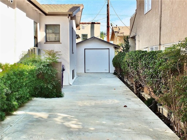 view of home's exterior with an outbuilding, driveway, a detached garage, and stucco siding