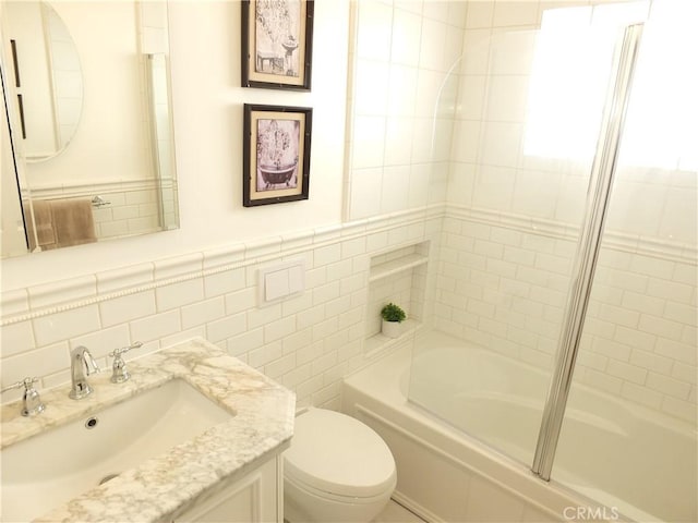 full bathroom featuring toilet, washtub / shower combination, tile walls, and vanity