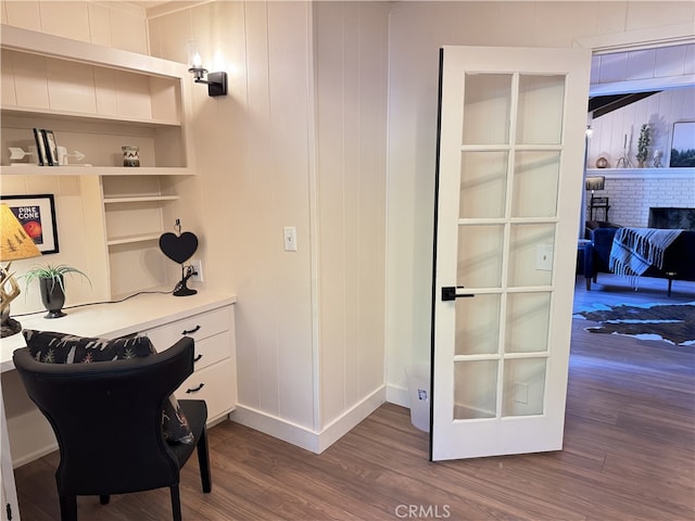 office area with dark hardwood / wood-style flooring and a brick fireplace