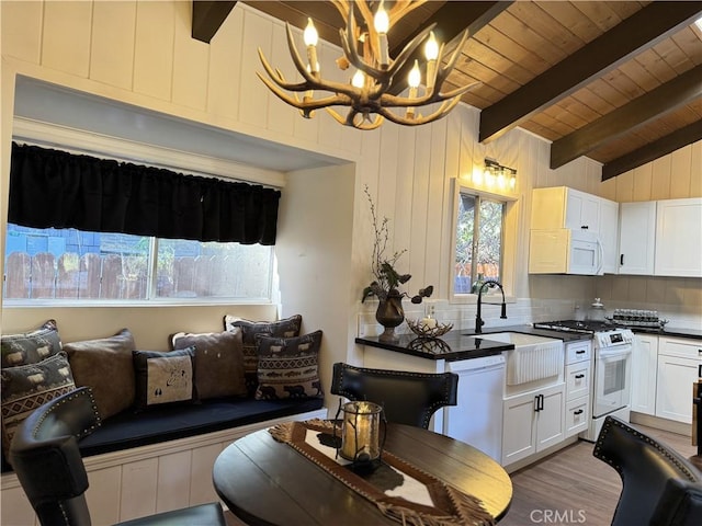 kitchen with pendant lighting, white appliances, lofted ceiling with beams, light hardwood / wood-style flooring, and a notable chandelier