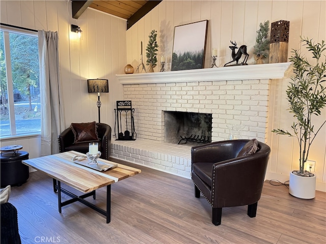 living room featuring a brick fireplace, wooden walls, plenty of natural light, and hardwood / wood-style flooring