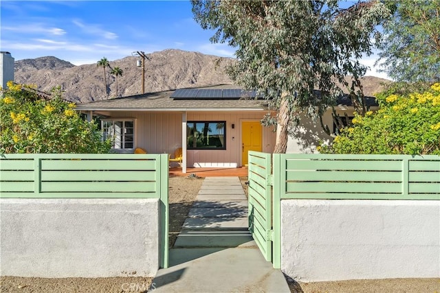 view of gate featuring a mountain view and solar panels