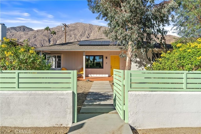 view of front facade with a mountain view, solar panels, and a porch