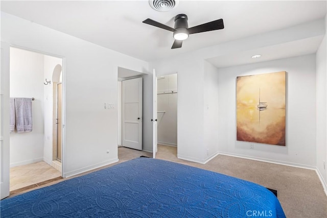 unfurnished bedroom featuring ensuite bath, ceiling fan, light colored carpet, a walk in closet, and a closet