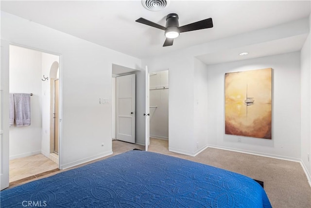 unfurnished bedroom featuring a spacious closet, light carpet, ceiling fan, and ensuite bath