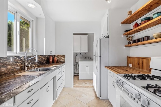 kitchen featuring tasteful backsplash, white appliances, sink, white cabinets, and washer / clothes dryer