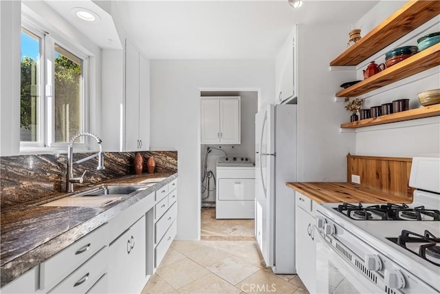 kitchen featuring white appliances, light tile patterned floors, sink, washer / dryer, and white cabinets