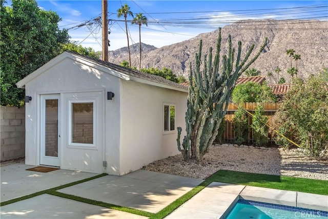 view of outbuilding with a mountain view, a patio area, and a fenced in pool