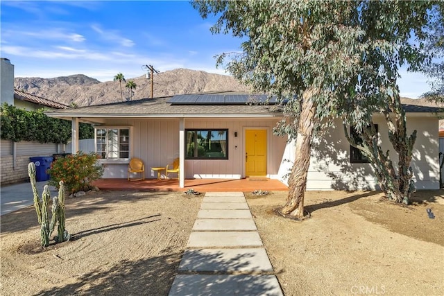 single story home featuring a deck with mountain view, solar panels, and a porch