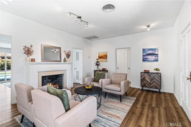 living room featuring dark wood-type flooring and a tiled fireplace