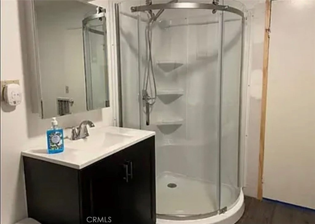 bathroom with vanity, wood-type flooring, and a shower with door