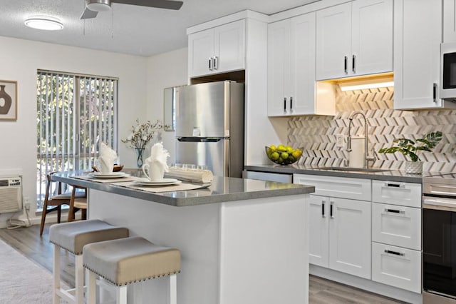 kitchen featuring a breakfast bar, white cabinets, sink, light hardwood / wood-style flooring, and stainless steel appliances